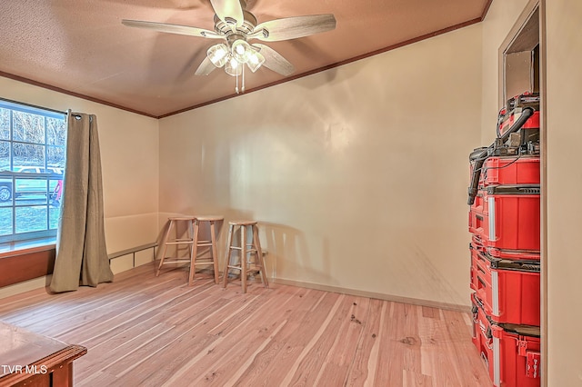 unfurnished room with a textured ceiling, light hardwood / wood-style flooring, ornamental molding, and ceiling fan