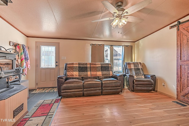 living room featuring ornamental molding, a healthy amount of sunlight, a barn door, and hardwood / wood-style floors