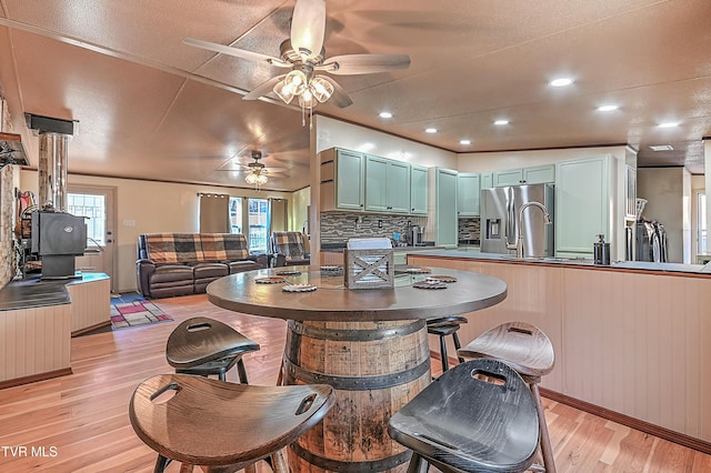 kitchen featuring tasteful backsplash, sink, stainless steel fridge, green cabinets, and light hardwood / wood-style flooring