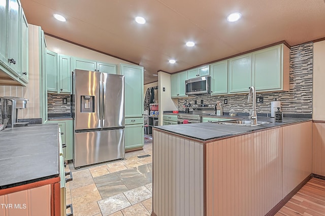 kitchen with tasteful backsplash, sink, kitchen peninsula, and appliances with stainless steel finishes