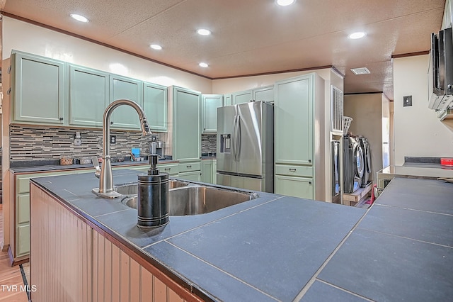 kitchen featuring tasteful backsplash, separate washer and dryer, crown molding, kitchen peninsula, and stainless steel refrigerator with ice dispenser