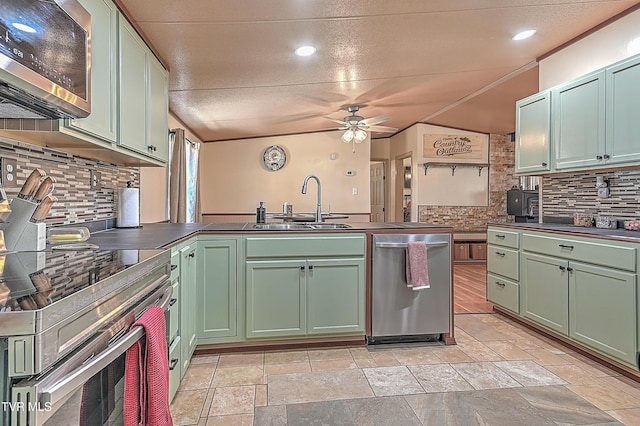 kitchen featuring sink, stainless steel appliances, green cabinetry, decorative backsplash, and kitchen peninsula