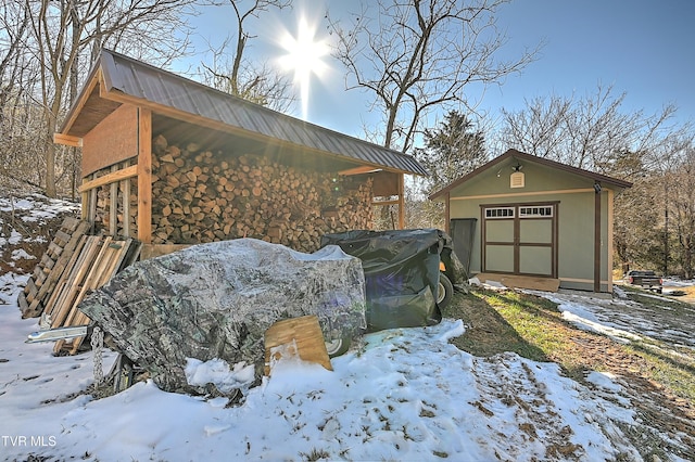 view of snow covered exterior with a garage and an outbuilding