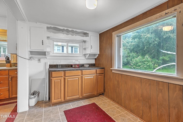 kitchen with plenty of natural light, light tile patterned floors, and wood walls