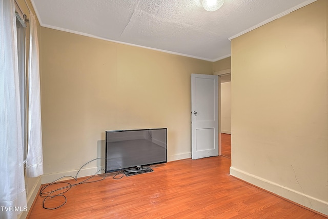 empty room featuring crown molding, a textured ceiling, and light hardwood / wood-style flooring