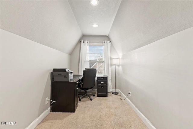 office area featuring light carpet, vaulted ceiling, and a textured ceiling