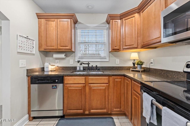 kitchen featuring dark stone countertops, sink, appliances with stainless steel finishes, and light tile patterned flooring