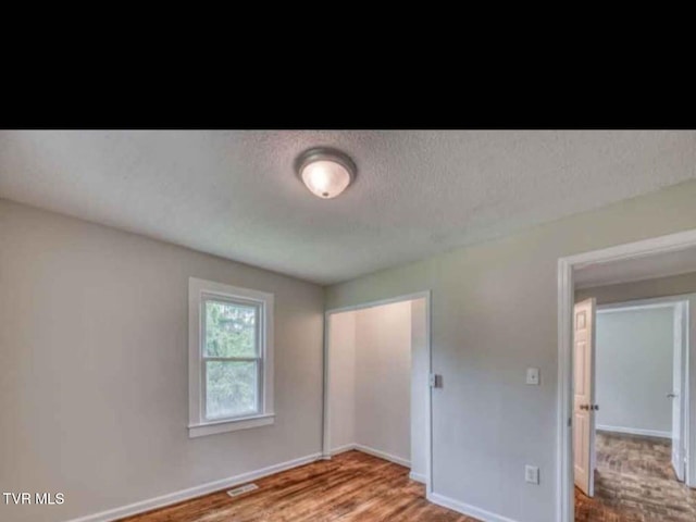 unfurnished bedroom with wood-type flooring and a textured ceiling