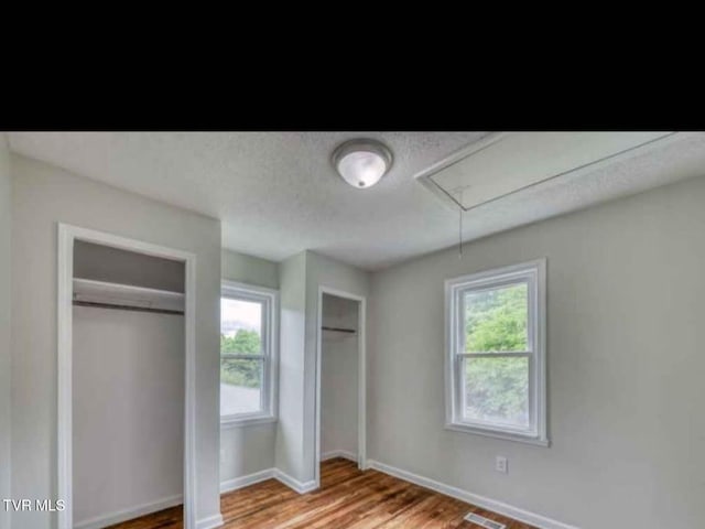 unfurnished bedroom with light wood-type flooring and multiple closets