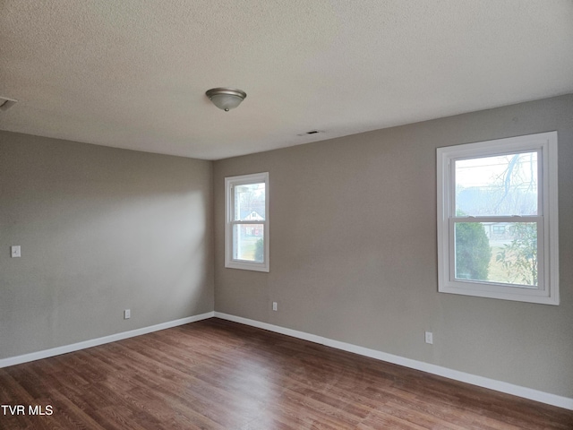 empty room with dark wood-type flooring and a textured ceiling