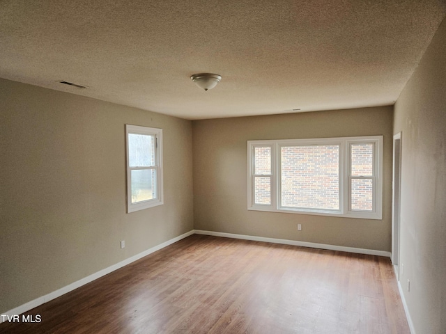 empty room with wood-type flooring and a textured ceiling