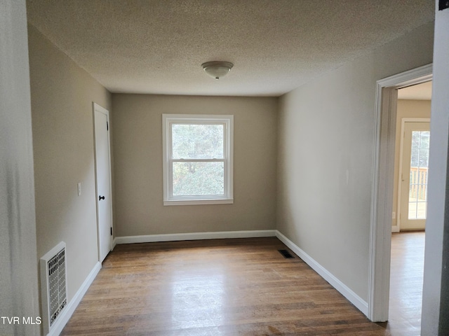 empty room with hardwood / wood-style flooring and a textured ceiling