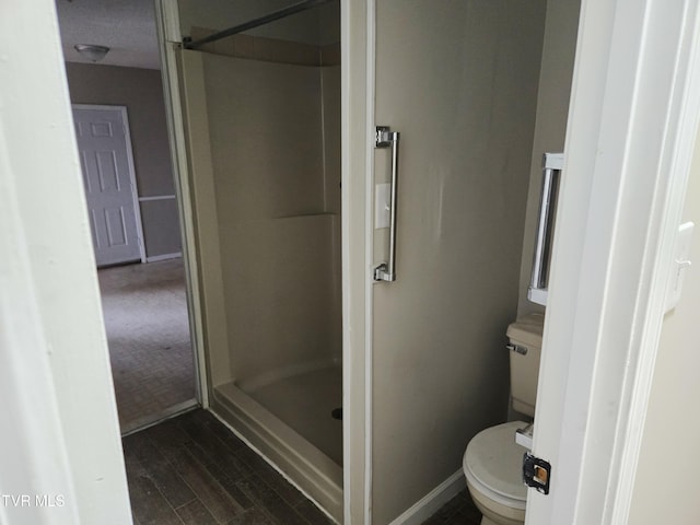 bathroom featuring wood-type flooring, a shower, and toilet