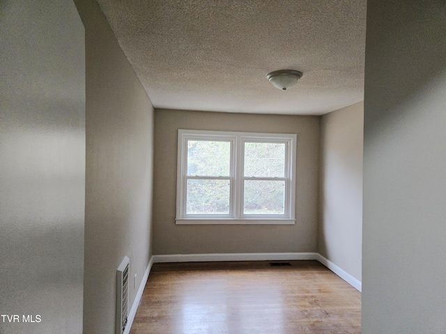 empty room featuring a textured ceiling and light wood-type flooring