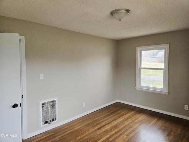 spare room featuring dark hardwood / wood-style floors and a textured ceiling