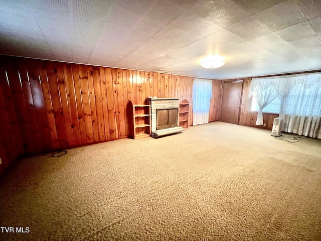 basement featuring carpet flooring, wooden walls, and a brick fireplace