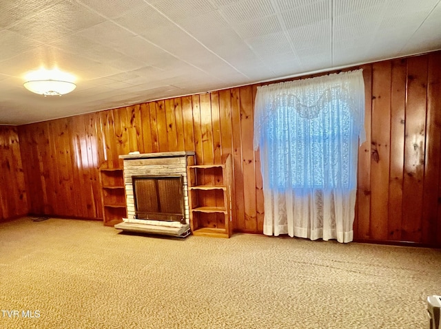 unfurnished living room featuring a fireplace, wood walls, and carpet floors