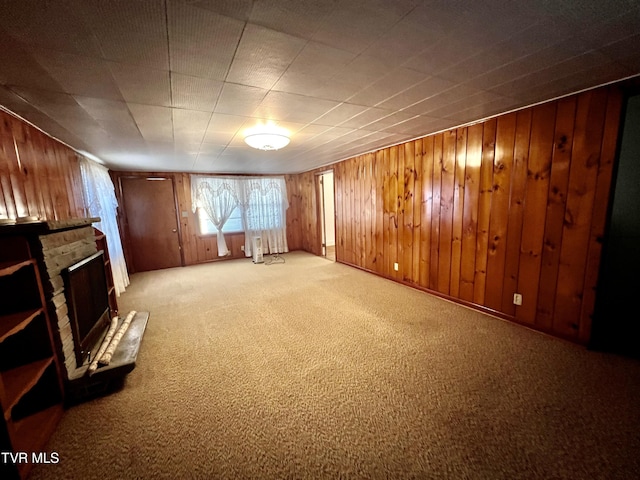 basement featuring light carpet, wood walls, and a stone fireplace