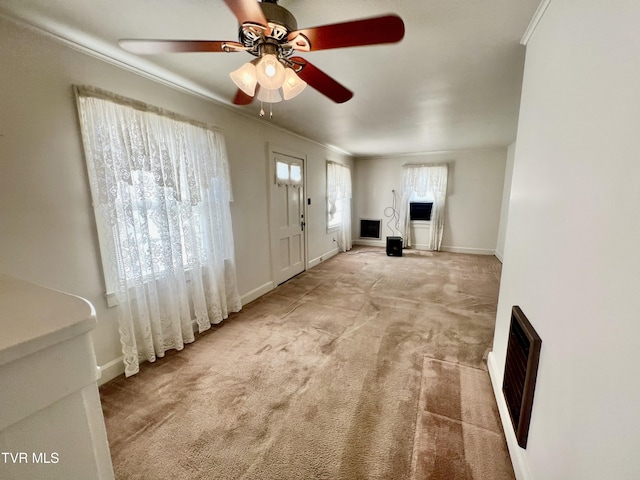 unfurnished living room with ornamental molding, ceiling fan, and light colored carpet