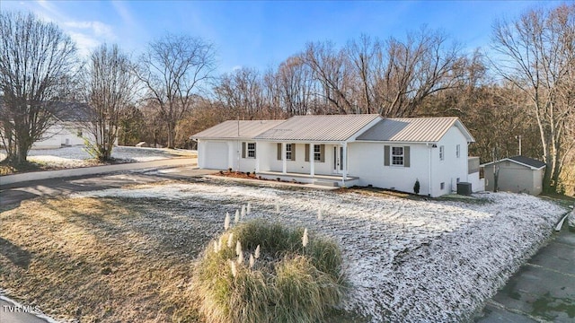 view of front of home featuring a garage, central AC unit, and a shed