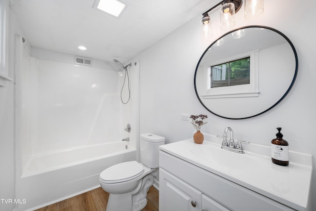 full bathroom featuring toilet, hardwood / wood-style floors, a textured ceiling, shower / bathtub combination, and vanity