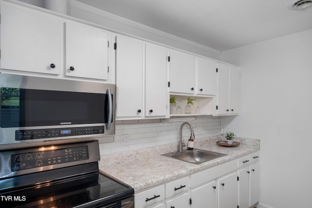 kitchen featuring decorative backsplash, sink, white cabinets, and appliances with stainless steel finishes