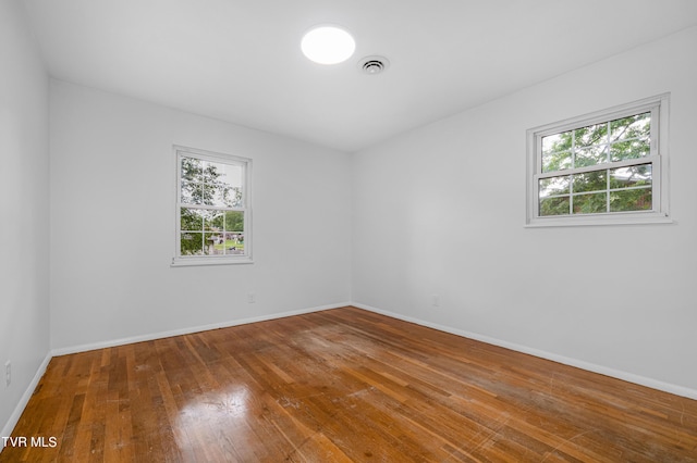 spare room with wood-type flooring and plenty of natural light