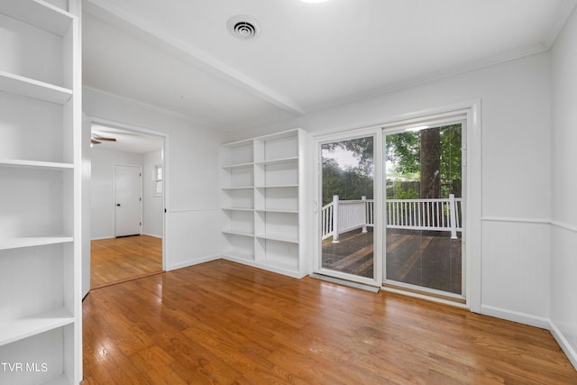 empty room featuring ceiling fan, built in shelves, beamed ceiling, and hardwood / wood-style floors