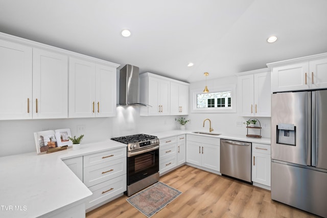 kitchen with appliances with stainless steel finishes, wall chimney range hood, and white cabinetry