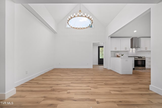 unfurnished living room featuring high vaulted ceiling, light wood-type flooring, baseboards, and an inviting chandelier