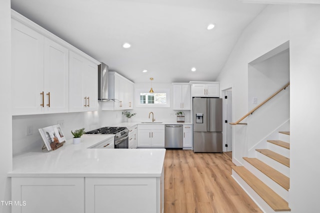 kitchen featuring white cabinetry, wall chimney range hood, stainless steel appliances, and light wood-type flooring