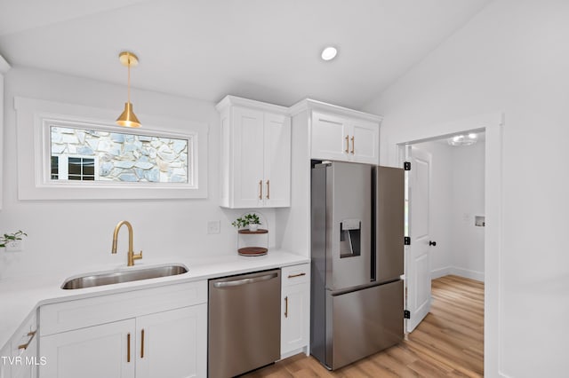 kitchen featuring white cabinets, lofted ceiling, stainless steel appliances, light countertops, and a sink