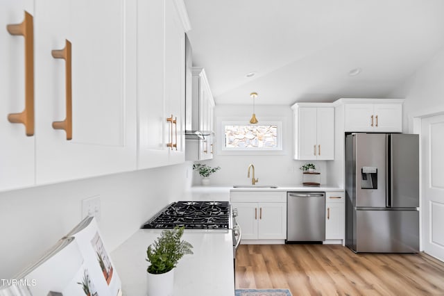 kitchen featuring white cabinetry, stainless steel appliances, light wood-type flooring, pendant lighting, and sink