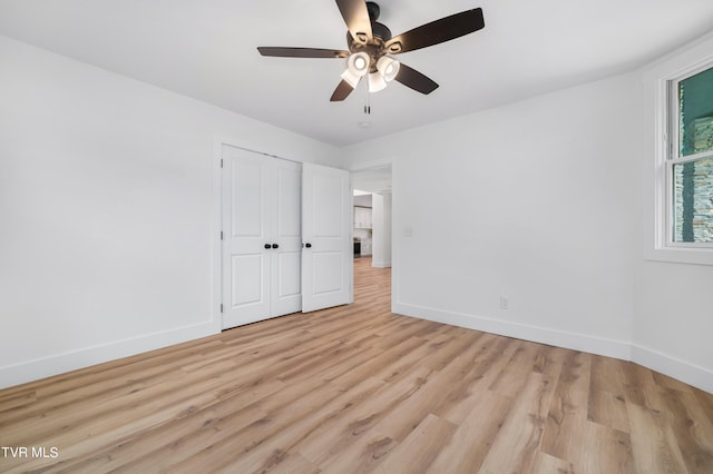 unfurnished bedroom with a closet, light wood-type flooring, a ceiling fan, and baseboards