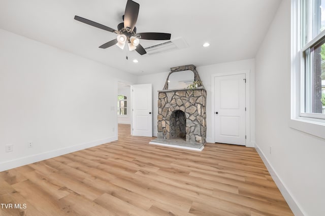 unfurnished living room with light wood finished floors, baseboards, a ceiling fan, a stone fireplace, and recessed lighting