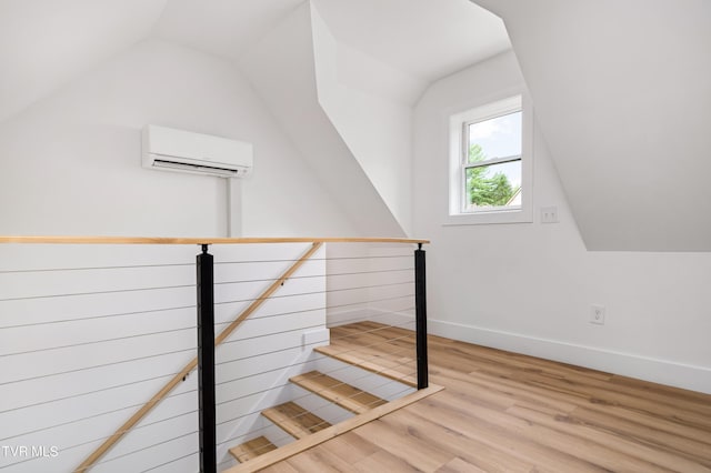 stairs with hardwood / wood-style floors, a wall mounted AC, and vaulted ceiling