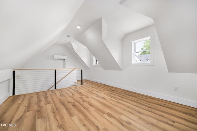 bonus room featuring light hardwood / wood-style floors, lofted ceiling, and a wall unit AC