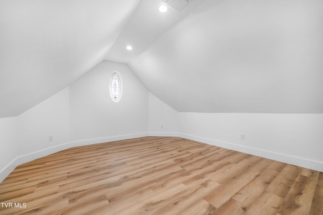 additional living space featuring vaulted ceiling and light hardwood / wood-style flooring