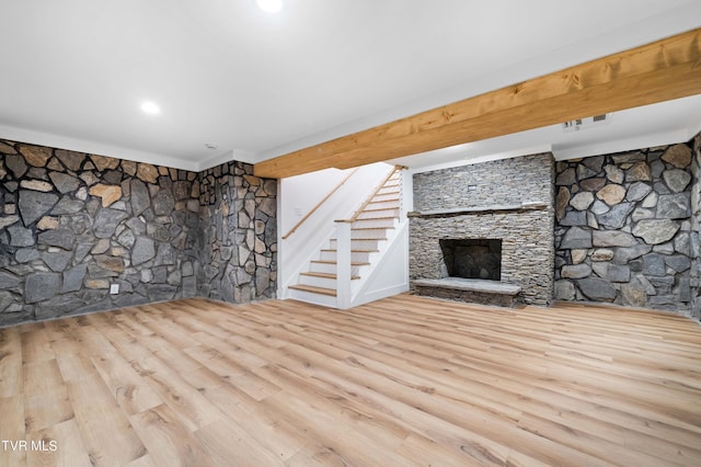 unfurnished living room with recessed lighting, stairs, wood finished floors, and a stone fireplace