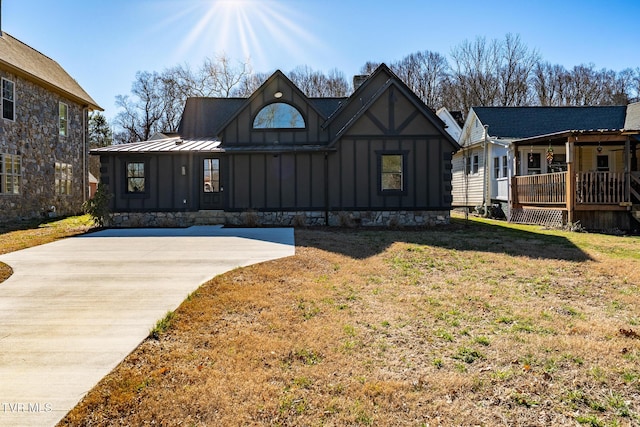 view of front of house featuring a standing seam roof, board and batten siding, a chimney, and a front yard