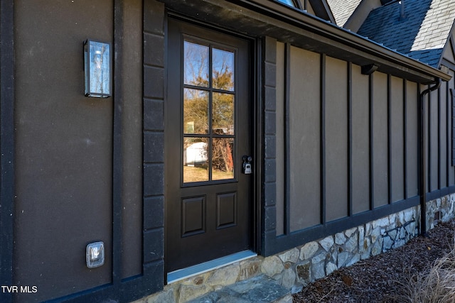 entrance to property featuring a shingled roof and board and batten siding