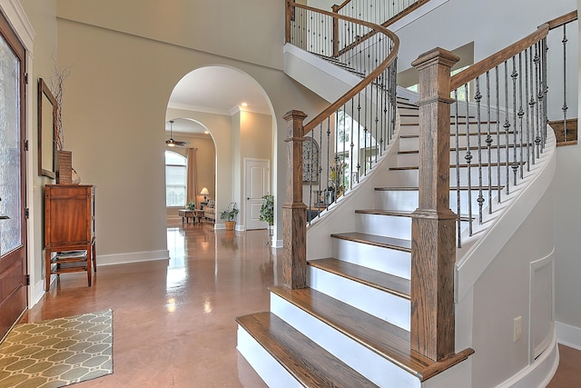 stairs featuring a high ceiling, ornamental molding, and concrete flooring