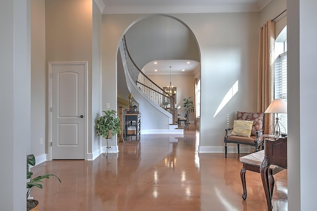 entrance foyer with a notable chandelier, a towering ceiling, crown molding, and concrete floors