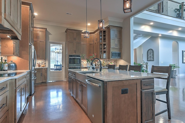 kitchen with a breakfast bar, appliances with stainless steel finishes, a center island with sink, and sink