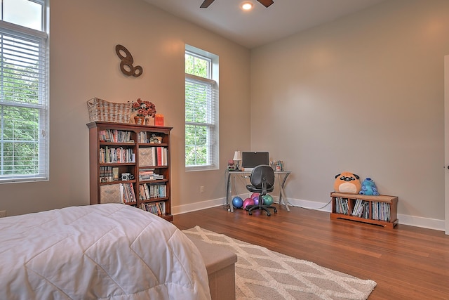 bedroom featuring ceiling fan, hardwood / wood-style flooring, and multiple windows