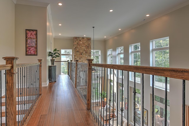 corridor featuring a healthy amount of sunlight, a towering ceiling, crown molding, and hardwood / wood-style floors