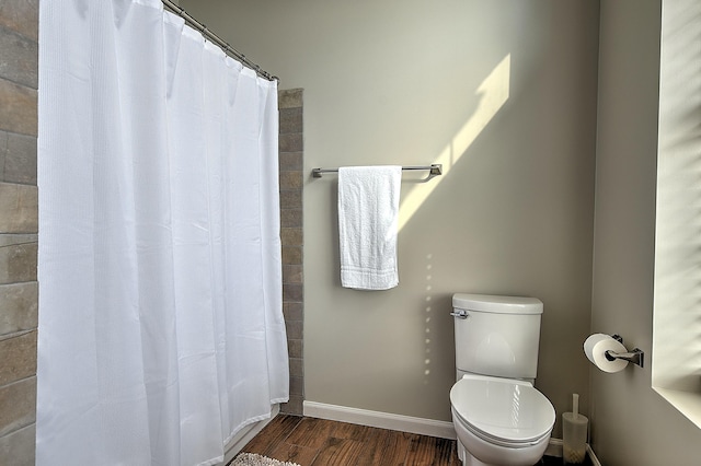 bathroom with toilet, curtained shower, and hardwood / wood-style floors