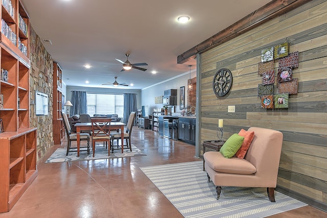 dining area featuring ceiling fan, concrete floors, and wood walls