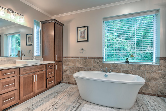 bathroom with a tub to relax in, vanity, tile walls, and plenty of natural light