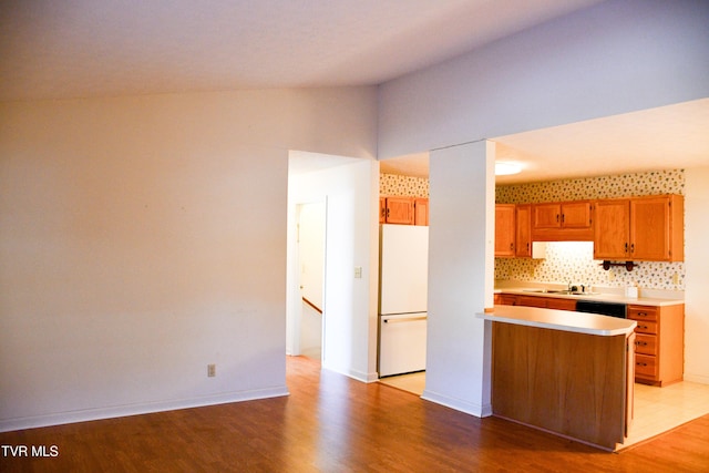 kitchen featuring lofted ceiling, black dishwasher, backsplash, white fridge, and light hardwood / wood-style floors